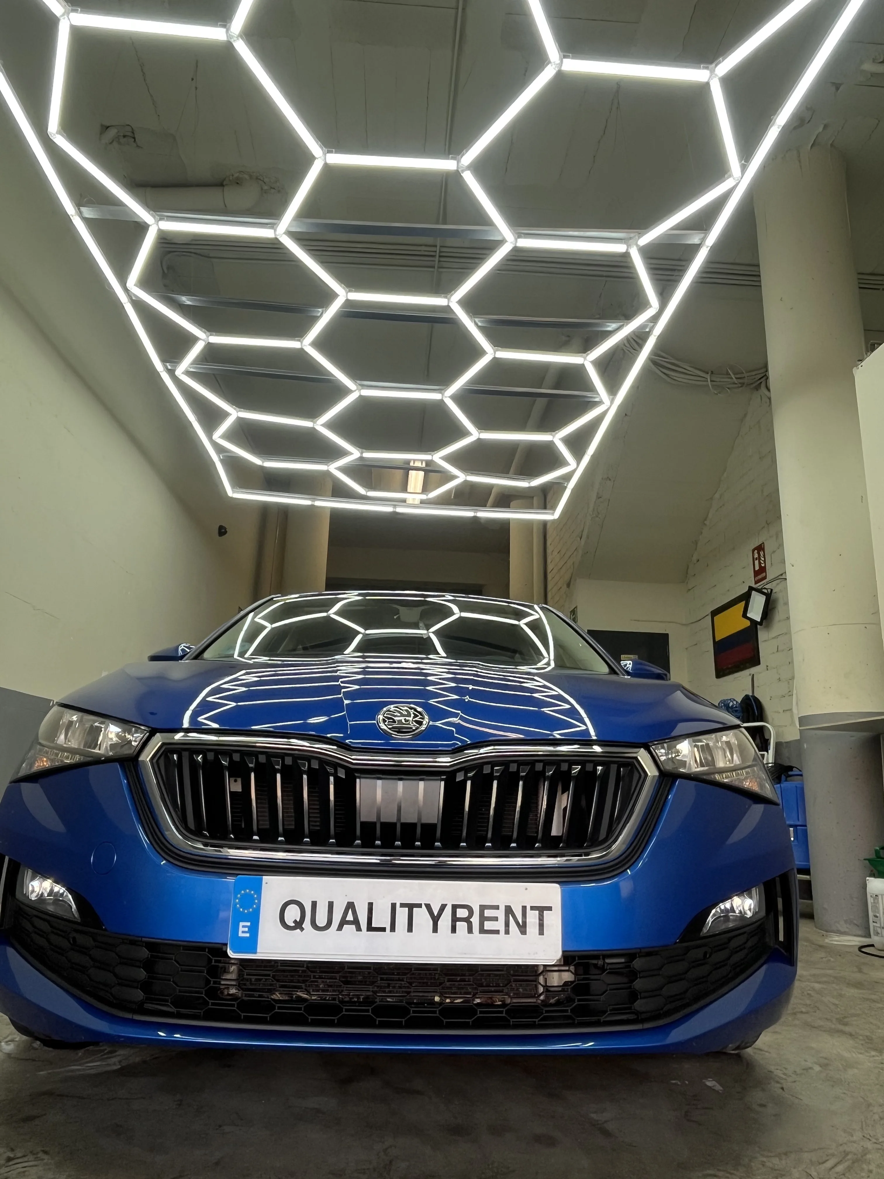 Skoda Scala azul de frente en el taller QualityRent bajo luces hexagonales